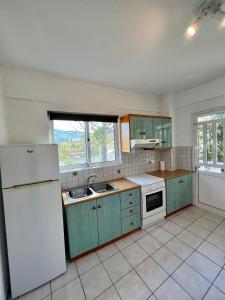 a kitchen with green cabinets and a white refrigerator at Alepochori Seaside Village in Kato Alepochori