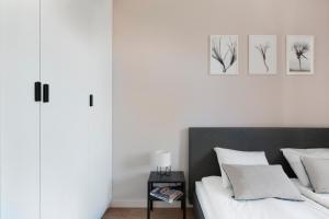 a bedroom with a bed with white sheets and a table at Elite Apartments Cityview Center in Gdańsk