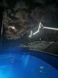 ein Haus in der Nacht mit Pool davor in der Unterkunft Chata pod Studničnou in Pec pod Sněžkou