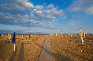 a row of umbrellas and chairs on a beach at Residence Schubert in Lignano Sabbiadoro