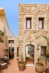 ein Steinhaus mit einer Terrasse mit Tischen und Stühlen in der Unterkunft Casa Di Veneto in Hersonissos