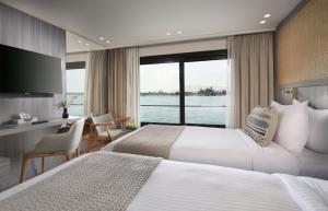 a hotel room with two beds and a desk and a window at Historia The Boutique Hotel Nile Cruise - Every Monday from Luxor for 04 & 07 Nights - Every Friday From Aswan for 03 & 07 Nights in Luxor +44 photos