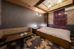 een slaapkamer met een bed, een tafel en een raam bij Hotel ニャンだふる in Himeji