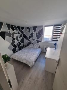 1 dormitorio con cama y pared geométrica en THELNA elya, en Bray-Dunes