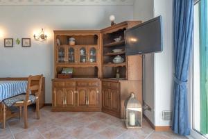 a living room with a tv and a wooden cabinet at Dimora imperiale Passo Mendola OSPITAR in Trento