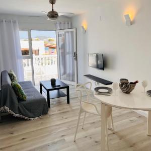 een witte woonkamer met een tafel en een bank bij Jacaranda Apartments & Studios in Es Cana