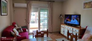salon z kanapą i telewizorem z płaskim ekranem w obiekcie WIFI Los Cisnes 2 dormitorios Primera Linea playa Ayamonte Isla Canela w mieście Isla Canela
