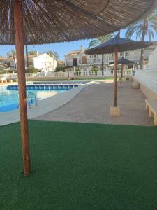 basen z 2 parasolami i zieloną trawą w obiekcie Bungalow Deluxe Gran Alacant w mieście Gran Alacant