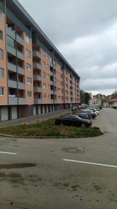 a parking lot with cars parked in front of a building at Apartman Andrej in Vranješ