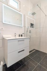 a white bathroom with a sink and a shower at Apartment Silvia in Trogir +21 photos