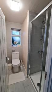 a bathroom with a toilet and a shower with a window at Dartford Kent House - Hosted by Castile Accommodations Ltd in Kent
