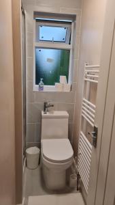 a small bathroom with a toilet and a window at Dartford Kent House - Hosted by Castile Accommodations Ltd in Kent +27 photos