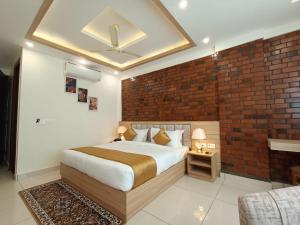 1 dormitorio con cama y pared de ladrillo en Hotel Royal Palm Dehradun en Dehradun