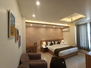 a hotel room with a bed and two chairs at Hotel Royal Palm Dehradun in Dehradun