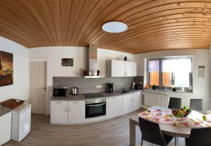 a kitchen with white cabinets and a wooden ceiling at Ferienhaus Wolle & Beate in Alken