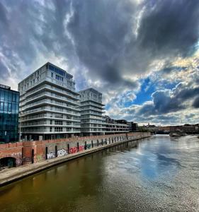 a river with two tall buildings next to a bridge at Piękny Apartament nad Odrą w centrum Wrocławia in Wrocław