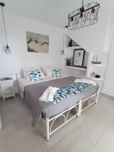 Kiki's Apartments في برباتي: غرفة نوم بيضاء بسرير ودرج