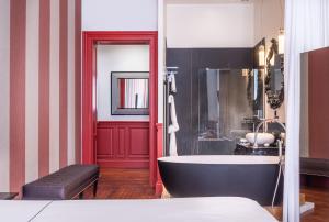 La salle de bains est pourvue d'une baignoire et d'une porte rouge. dans l'établissement Le Palais Gallien Hôtel & Spa, à Bordeaux