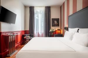a hotel room with two beds and a television at Le Palais Gallien Hôtel & Spa in Bordeaux