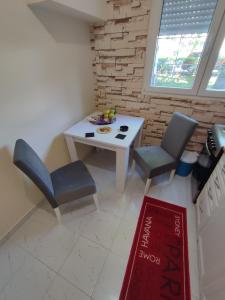 een kleine keuken met een witte tafel en stoelen bij Orion Apatman in Belgrado