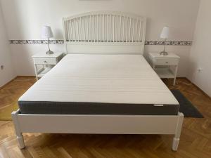 a bed in a room with two night stands and two lamps at Pálma apartman in Szentes