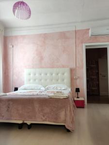 una camera da letto con un grande letto con una parete rosa di Hotel Glicine a Noli