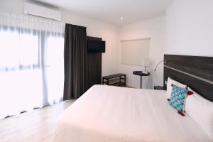 - une chambre avec un grand lit blanc et une tête de lit en bois dans l'établissement Appart' Hotel La Girafe Marseille Est - Porte d'Aubagne, à La Penne-sur-Huveaune