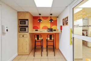 a kitchen with two stools and a counter in a room at Première Classe Lille Sud Henin Beaumont in Noyelles-Godault +17 photos