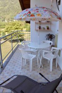 un patio con mesa, sillas y sombrilla en All'Ombra del Mortirolo, en Mazzo di Valtellina