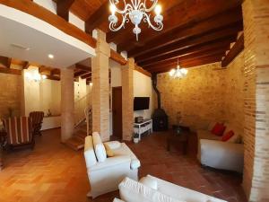 a living room with white furniture and a chandelier at Alojamiento Gaia in Aldeasoña