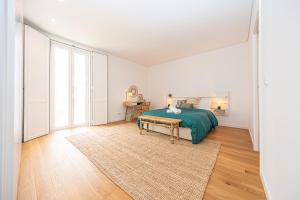 a white bedroom with a green bed and a rug at Apartamento situado na zona costeira da cidade in Setúbal