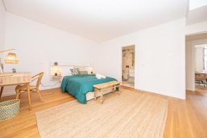 a white bedroom with a bed and a table at Apartamento situado na zona costeira da cidade in Setúbal