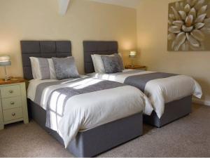 a bedroom with two beds and a painting on the wall at 2 Mews Cottages - Town Centre Location in Appleby