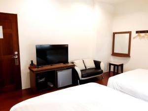 馬公市的住宿－筠妍小棧，客房设有两张床、一台电视和一把椅子。