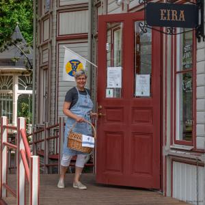 Una donna in piedi davanti a una porta rossa di Villa Eira vandrarhem a Hjo