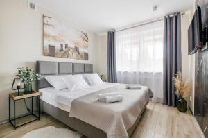 a bedroom with a large bed with two towels on it at Apartamenty Mieszka I in Łódź