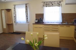 a kitchen with a table with a vase of flowers at Elixír Apartman in Villány
