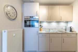 フーズムにあるImmenseeの白いキャビネットと壁掛け時計付きのキッチン