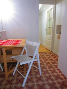 una silla blanca sentada junto a una mesa con una mesa roja y blanca en Largo da Paz 24, en Lisboa