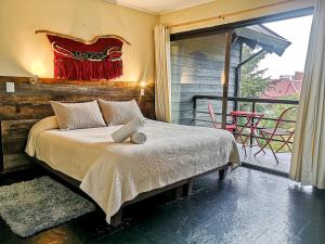 a bedroom with a bed and a balcony with a table at Newen B&B in Pucón