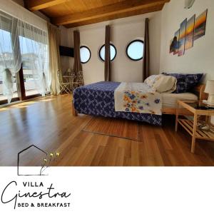 a bedroom with a bed and two windows and a wooden floor at B&B Villa Ginestra in Pescara