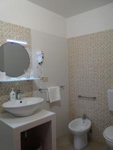 een badkamer met een wastafel, een toilet en een spiegel bij B&B Vinci in Noto