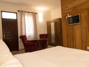 um quarto com uma cama, uma mesa e cadeiras em Mkomazi Hotels and Camps em Hegoma