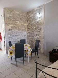 una sala da pranzo con tavolo, sedie e muro di mattoni di Appartamenti San Vito a San Vito