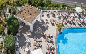 a beach with a pool, chairs, tables, and umbrellas at TUI Blue Gardens - Adults-only - Savoy Signature in Funchal