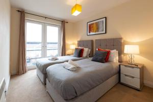 two beds in a bedroom with a large window at BEST PRICE! Superb city centre apartment, 2 Superkings or 4 singles Smart TV & Sofa bed- FREE SECURE PARKING in Southampton