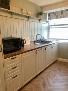 a kitchen with white cabinets and a sink and a microwave at Cranwell Court Apartments in Aberystwyth