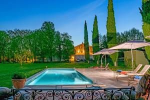 a swimming pool with two umbrellas and a house at Bastide de Bellegarde in Avignon