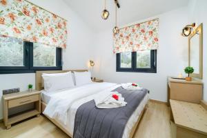 a bedroom with a bed and two windows at Serenity Apartments in Skala Potamias