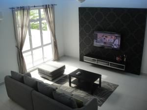 a living room with a couch and a tv at Batu Ferringhi - Shamrock Beach Villas, Penang in Batu Ferringhi